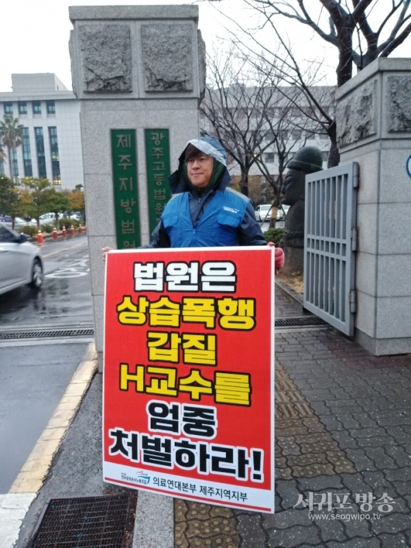 의료연대제주지부가 법원 앞에서 상습폭행·갑질 제주대학교병원 H교수의 엄중처벌을 촉구하는 1인 피켓시위를 하는 모습