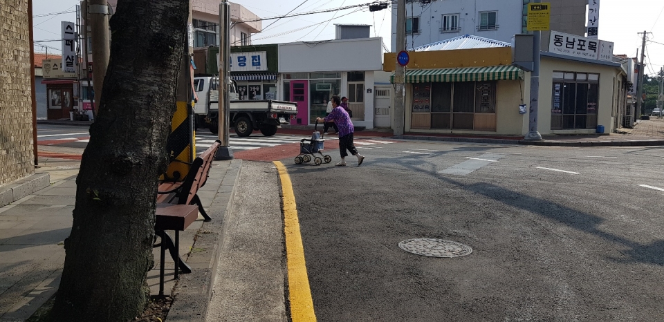 고성 오일시장을 이용하면서 횡단보도 턱이 높기 때문에 무거운 짐을 실은 유모차 이용 노인분들이 도로를 횡단 할 수밖에 없는 현실이다.(사진 고기봉 기자)