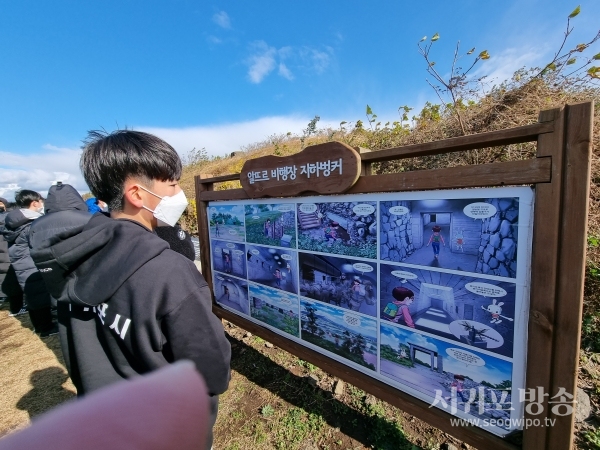 탐방에 참가한 청소년들이 지하벙커 해설표지판을 살펴보고 있다