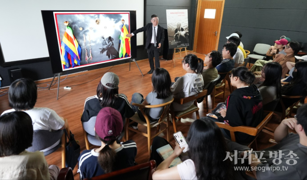 해녀와 심방과의 밀접한 관계와 사진 위에 심방의 오방색 기와 용품들을 콜라주한 이유 등을 설명하고 있는 양종훈 교수