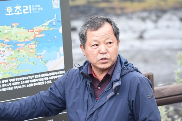 오조리 고기봉 이장의 오조리 종합 안내도 앞에서 연안습지 보호구역 지정 및 마을에 대한 해설을 하는 모습